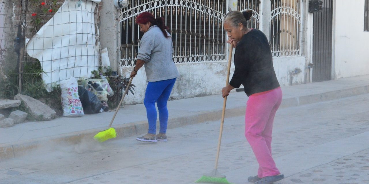 Vecinos limpian el frente de su casa